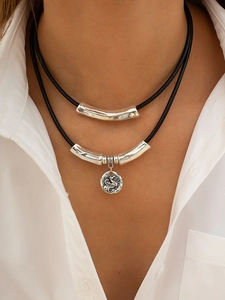 Detail of double-layer necklace with vintage relief pendant and silver curved tubes