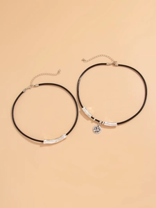 Detail of double-layer black cord necklaces with silver relief pendant and metal tubes