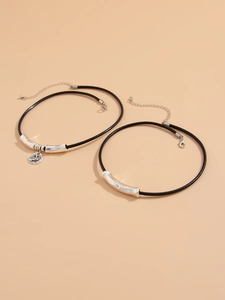 Detail of double-layer black cord necklace with vintage relief pendant and silver tubes