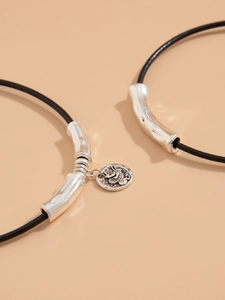 Detail of layered black cord necklaces with vintage silver tubes and embossed coin pendant