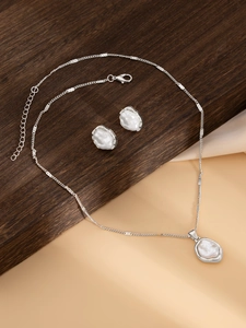 Vue détaillée du collier argenté avec pendentif perle et boucles d'oreilles assorties