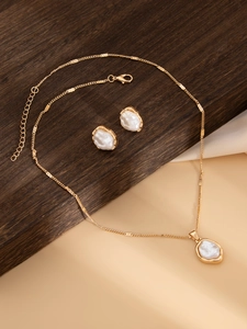 Détails d'un collier en perles baroques et boucles d'oreilles sur support en bois