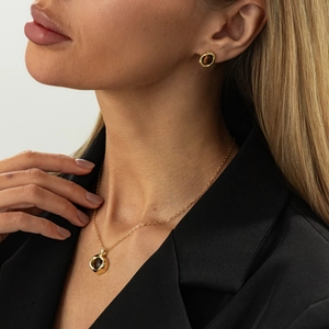 Parure collier et boucles d'oreilles dorés avec pierres brunes portée par un mannequin