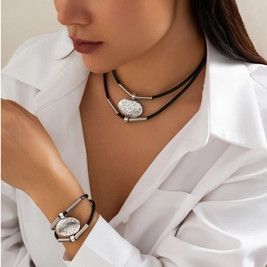 Double-layered tube necklace and bracelet set with textured oval relief charms on a model