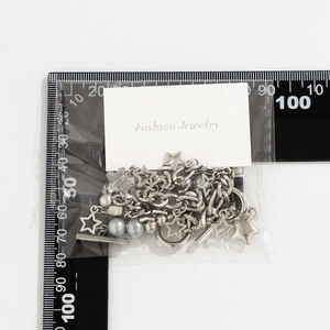 Silver star pendant necklace with chain and pearls displayed next to a size ruler