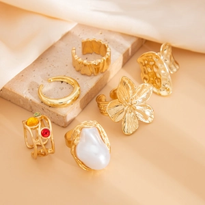 Detail view of vintage gold rings set featuring flower pearls and colorful gemstones