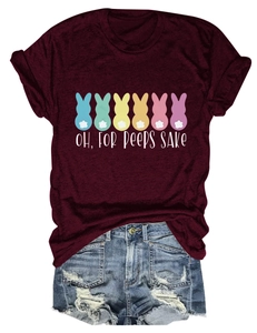 Flat lay view of a burgundy T-shirt with Easter bunny graphics and denim shorts on white