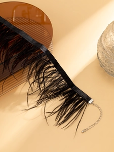 Détail d'un choker en plumes noires avec ruban de satin et chaîne réglable en argent