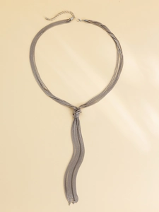 Detail of silver layered necklace with central knot design and hanging metal tassels