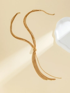 Macro detail of gold multi-layer tassel necklace with elegant knot on minimalist background