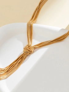 Detail shot of multilayered gold box chains with a unique knotted tassel design on stone