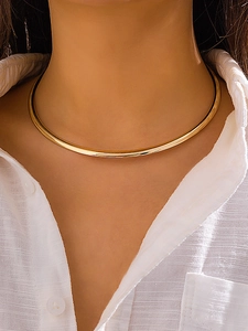 Gros plan d'un collier ras du cou doré minimaliste avec une finition métallique polie
