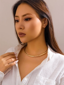 Gros plan d'un choker doré minimaliste avec une finition miroir polie sur un modèle