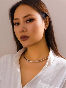 Détail d'un collier ras de cou en métal argenté poli brillant porté par un mannequin