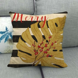 Close-up of linen pillow cover with gold palm leaf, red berries and Merry text detail