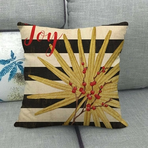 Close-up of linen pillow cover with gold palm leaves and red Joy script on sofa