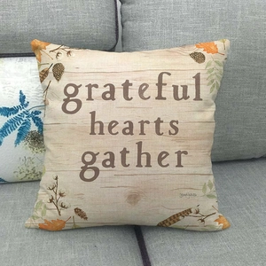 Close-up of linen pillow cover with grateful hearts gather text and autumn leaves