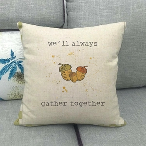 Close-up of Happy Fall linen pillow cover with printed acorn design on a grey sofa