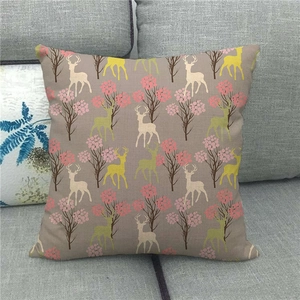 Linen decorative pillowcase featuring cartoon reindeer and forest pattern on a grey sofa