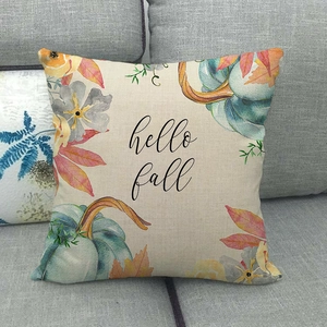 Detail of linen pillow cover with pumpkins and Hello Fall text on a grey sofa