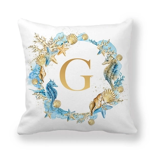 Detail of soft peach skin pillow cover with golden letter G and sea creature wreath