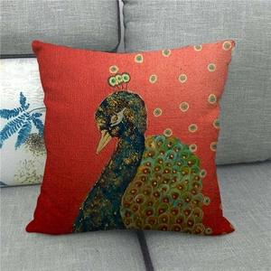 Detail of colorful peacock print on red linen pillowcase showing texture on a grey sofa