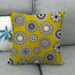 Detail of geometric mandala pattern on mustard yellow linen cushion cover on grey sofa