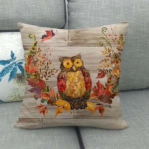 Detail of cute owl pillowcase on grey sofa featuring autumn maple leaves and wood texture