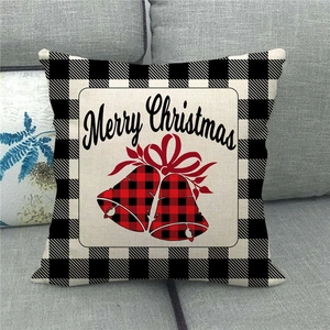 Close-up of Merry Christmas linen pillow cover with buffalo plaid pattern on a gray sofa