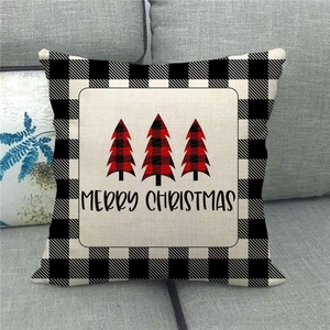 Close-up of linen Christmas pillowcase with buffalo plaid trees on a grey sofa