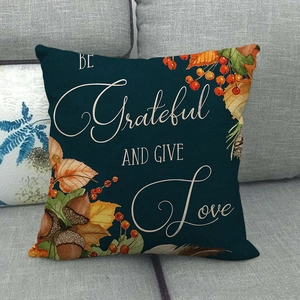 Détail de la housse de coussin en lin avec citation BE Grateful AND GIVE Love sur canapé