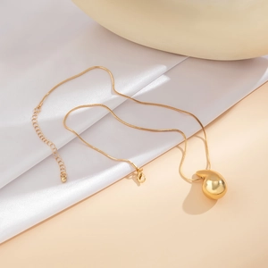 Macro detail of polished gold teardrop pendant necklace with glossy mirror finish