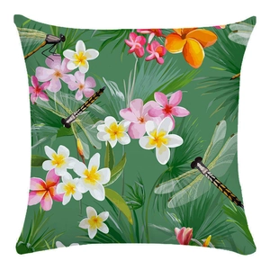 Detail of tropical throw pillow case with green leaves, plumeria and dragonflies