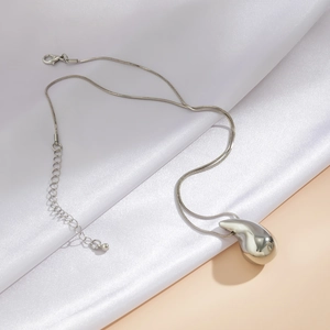 Macro detail of silver-toned drop pendant with high-shine mirror finish on snake chain