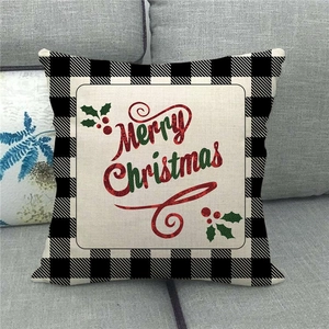 Detail of Merry Christmas linen pillowcase with buffalo plaid borders on a gray sofa