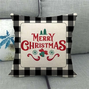 Close-up of Merry Christmas linen pillow cover with buffalo plaid border on a sofa