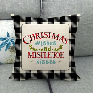 Detail of linen Christmas pillow case with buffalo plaid and festive quote on gray sofa