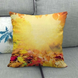Linen autumn maple leaf pillowcase with orange and red foliage on a grey sofa