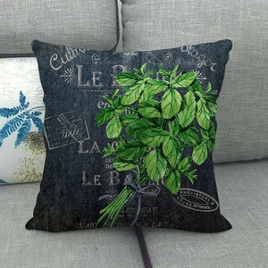 Vintage botanical linen pillowcase with green herbs and French script on gray sofa