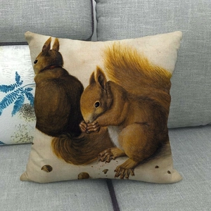 Détail d'une housse de coussin en lin avec motifs d'écureuils sur un canapé gris