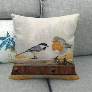 Détail d'une housse de coussin en lin avec illustration d'oiseaux sur un canapé gris