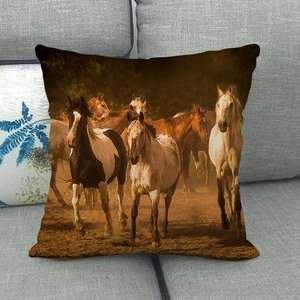 Linen pillowcase with vintage running horses oil painting on a gray sofa