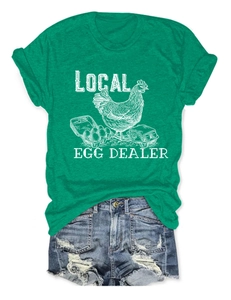 Flat lay of green t-shirt with retro white Local Egg Dealer hen print and denim shorts