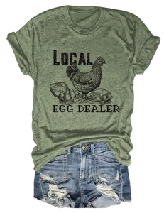 Detail of Local Egg Dealer retro graphic on grass green cotton t-shirt with denim shorts