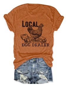 Flat lay of an orange cotton t-shirt with local egg dealer print and denim shorts