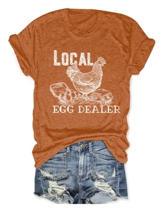Flat lay of caramel orange T-shirt with Local Egg Dealer print and denim shorts