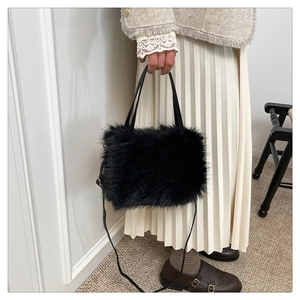 Detail van zwarte faux fur handtas met zachte textuur en verstelbare lederen riem