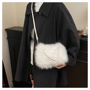 Detail van witte crossbodytas van imitatiebont met gouden haken op zwarte jas
