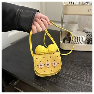 Handheld detail of yellow mini crossbody bag with a bow and 3D felt flowers