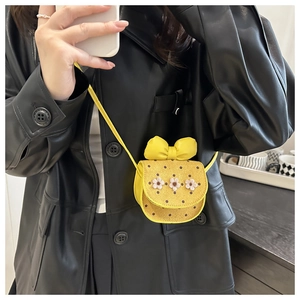 Close-up of yellow mini crossbody bag with polka dots and bow on a model